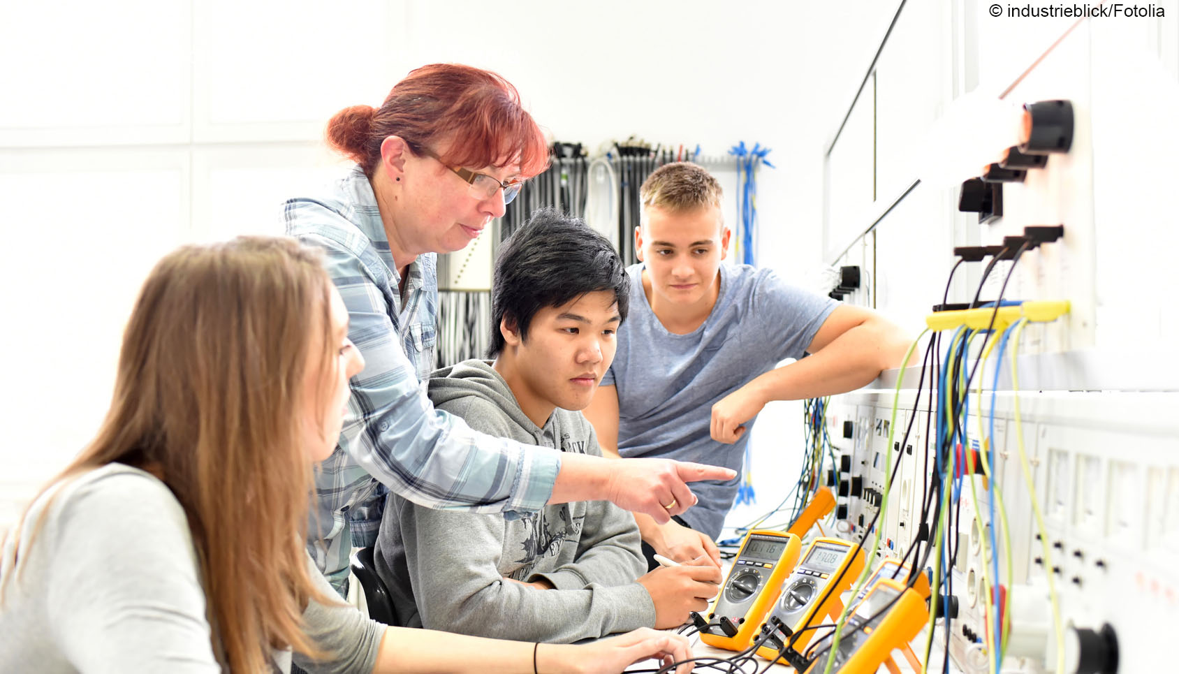 drei Jugendliche schauen sich elektrische Messgeräte an