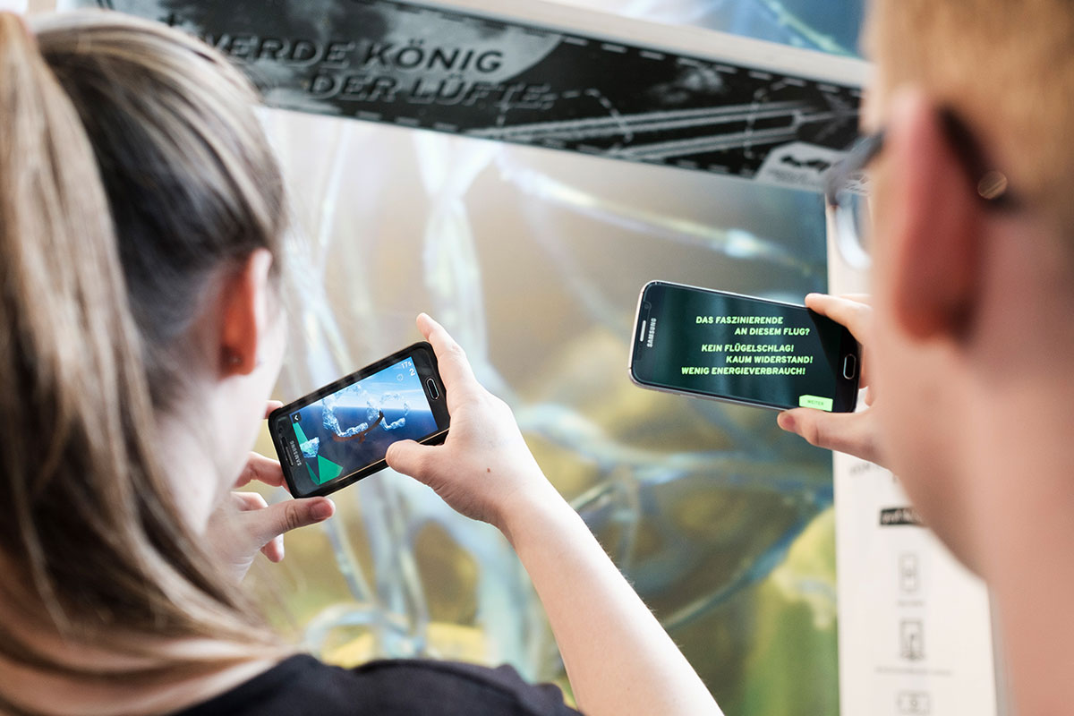 Zwei Jugendliche in der Ausstellung mit Smartphones