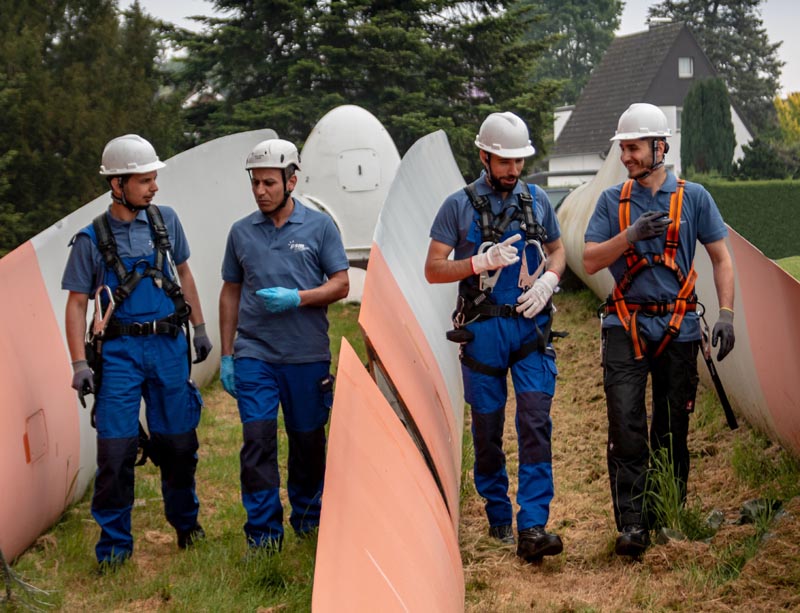 © psm GmbH & Co. KG Vier Männer mit Rotorblättern einer Windkraftanlage